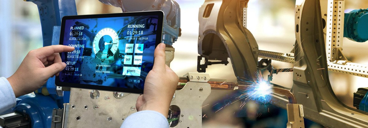 two hands holding ipad device tracking performance of functioning manufacturing equipment 