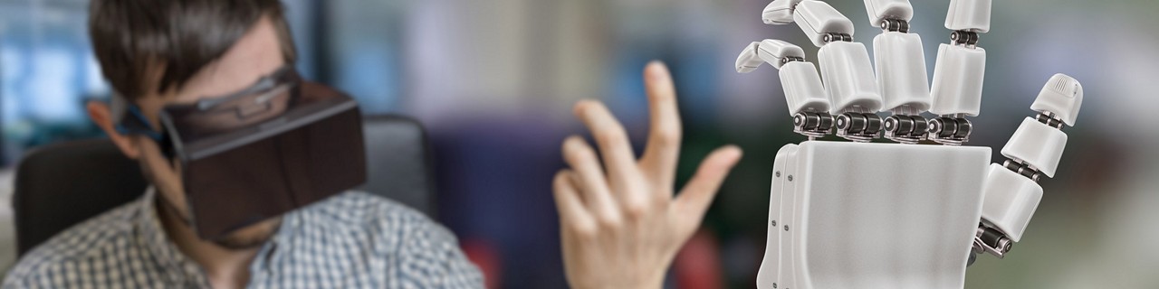 Man wearing a VR headset and doing hand moments along with a robotic hand